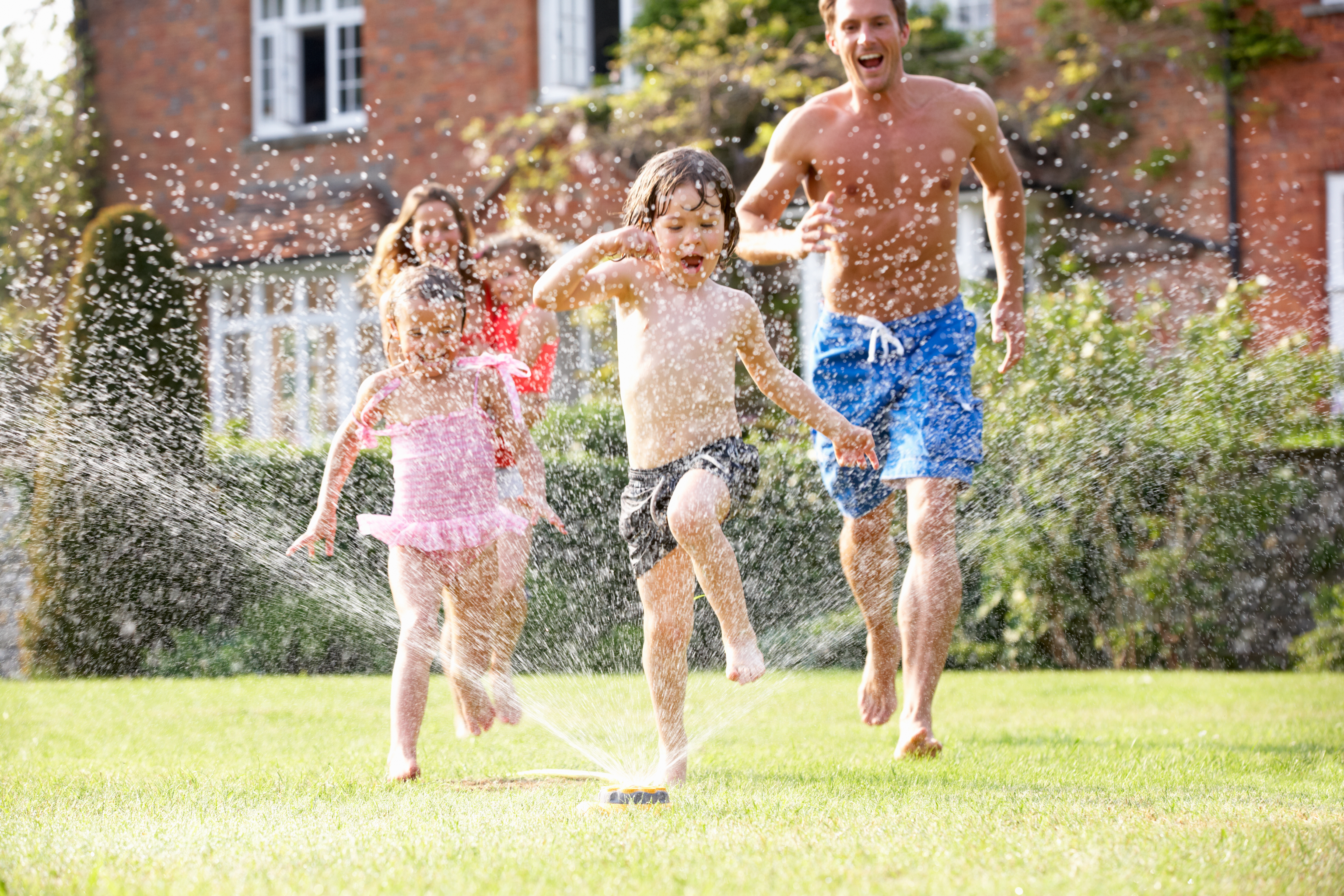 South Jersey family playing in the water sprinkler outside